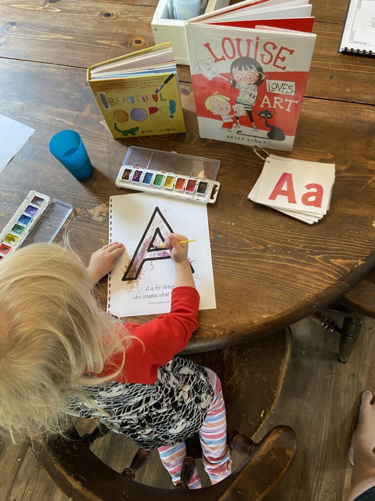 Child painting a letter A worksheet with watercolors