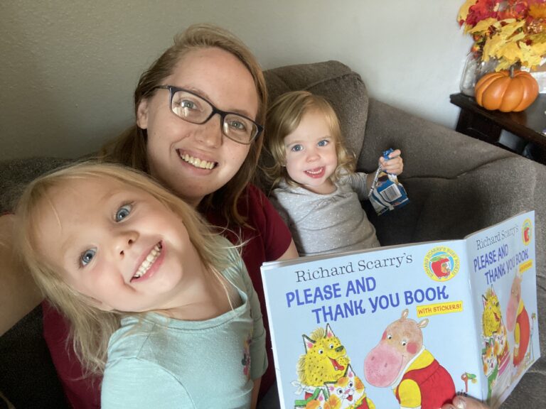 Katie taking a selfie with her daughters and a picture book