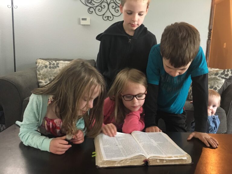 Kids gathered around reading a book together