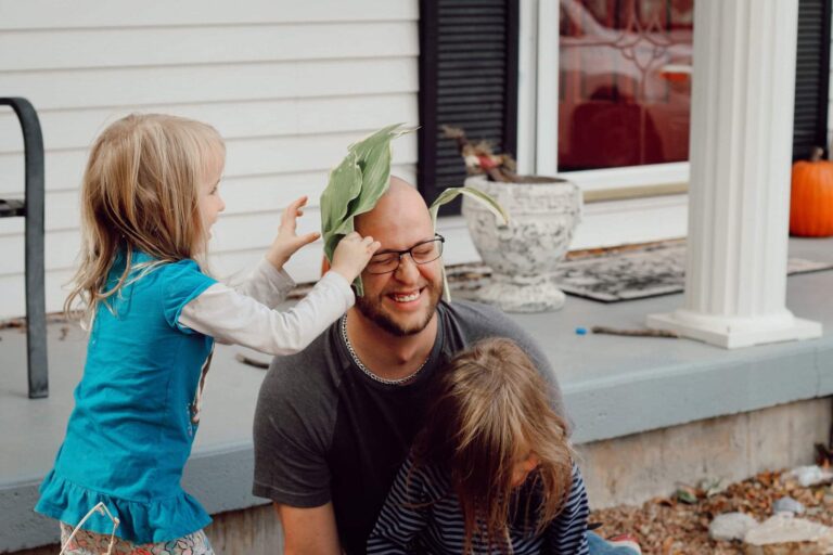 Dad laughing as his daughter puts a leaf on his head